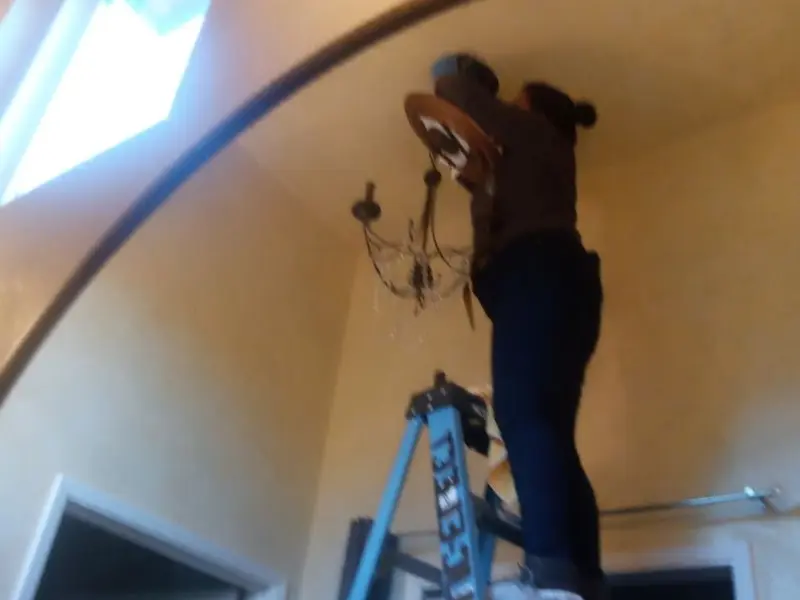 Electrician installing a chandelier in a Ladera Heights residence